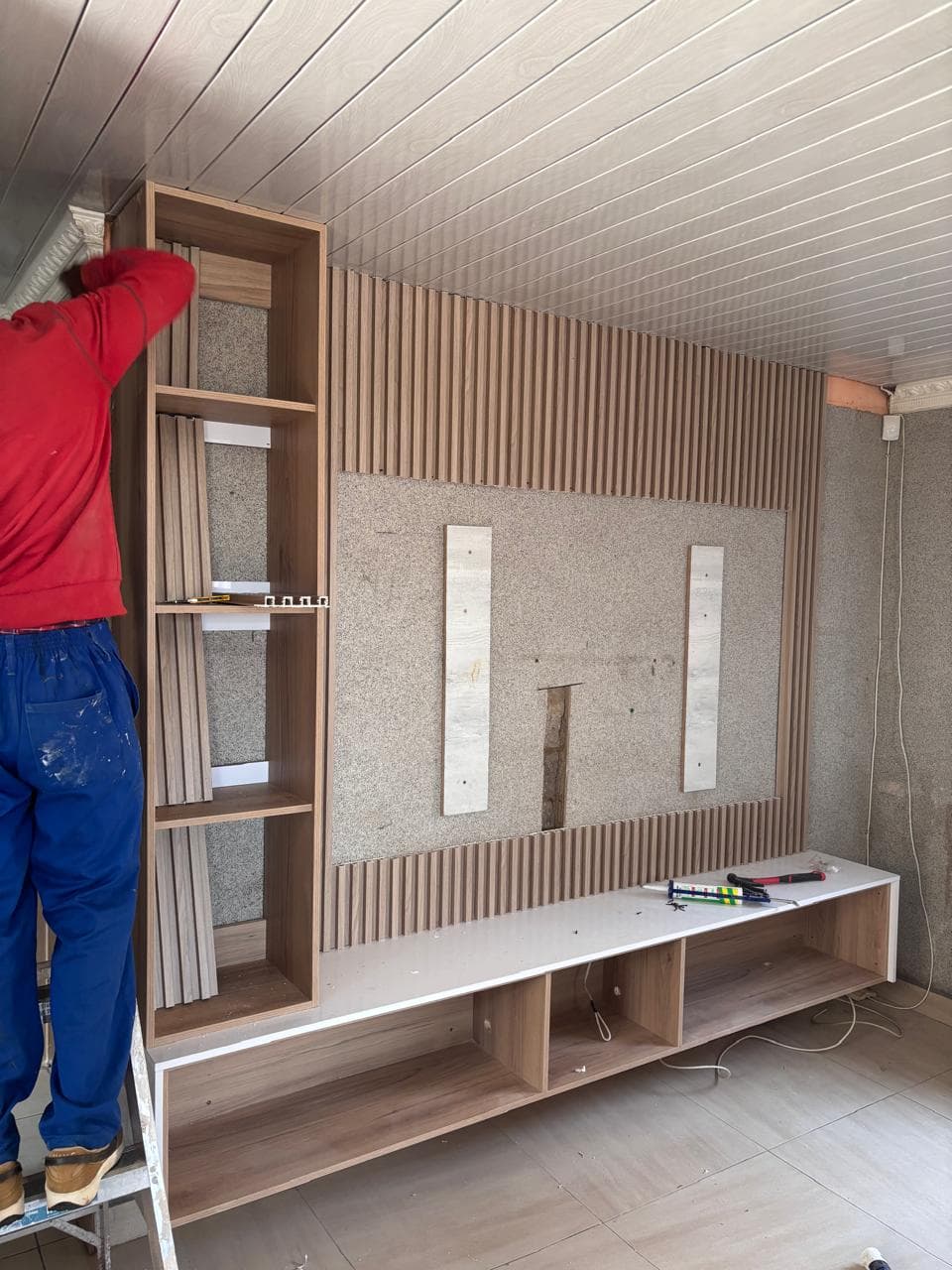 Gelsco team installing an oak slatted TV feature wall