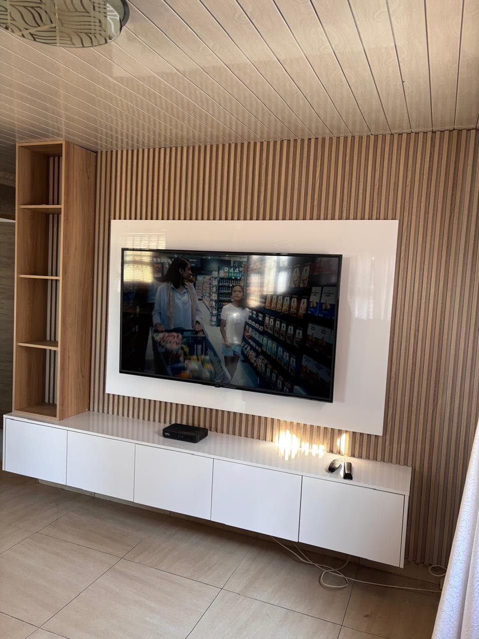 Light oak slatted TV feature wall with a white floating console